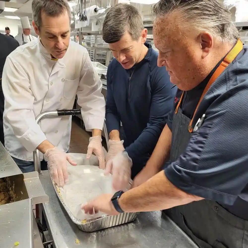 three chefs working on a dish