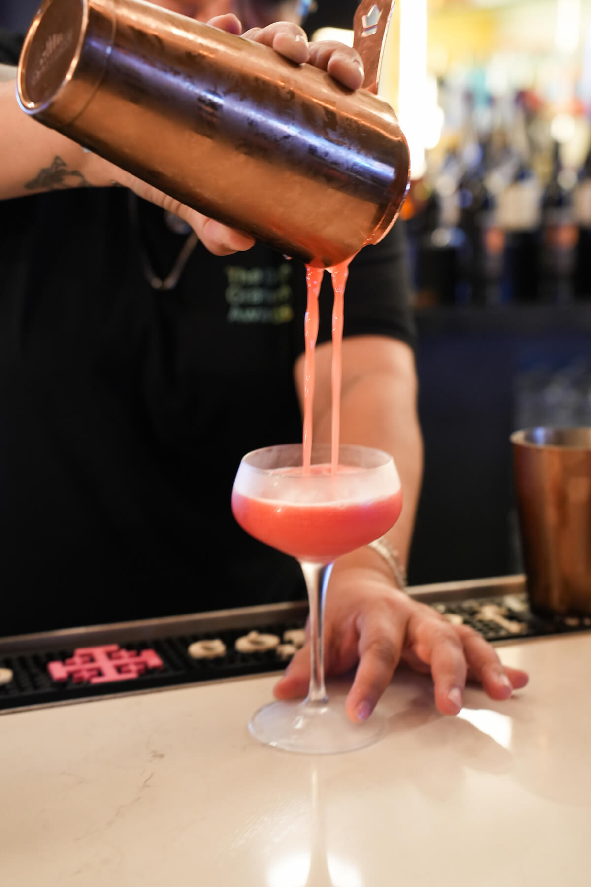 Pink cocktail being poured into a glass